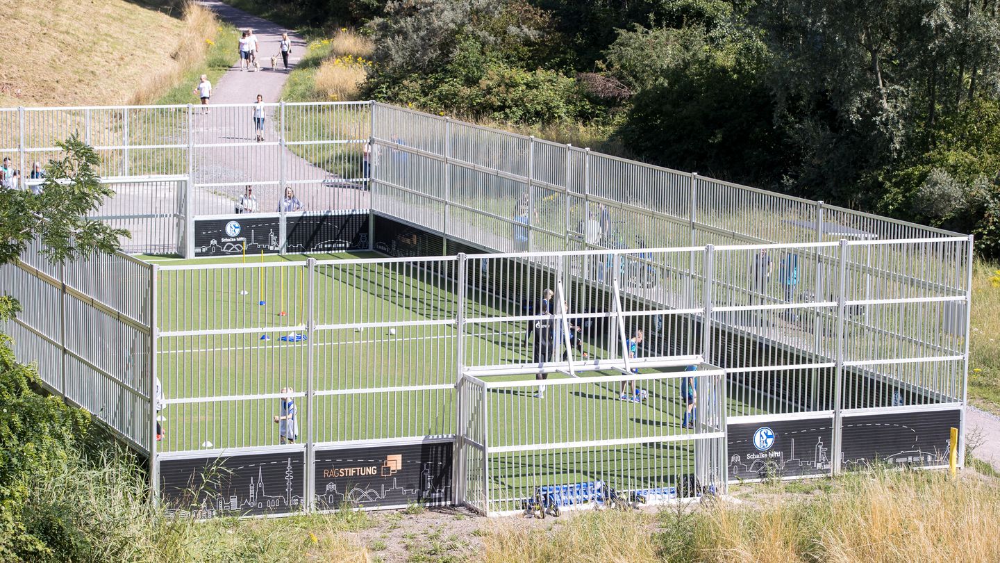 Ein Bolzplatz von schräg oben aufgenommen, auf dem sich einige Kinder befinden.