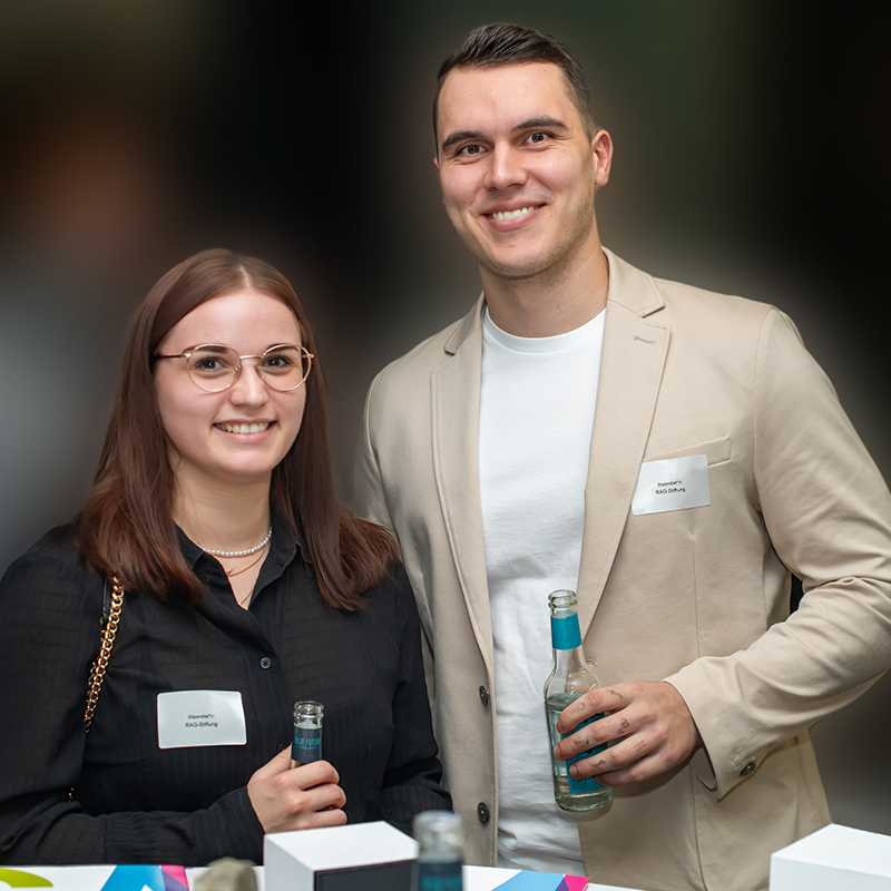 Eine Studentin und ein Student stehen nebeneinander in feierlicher Atmosphäre