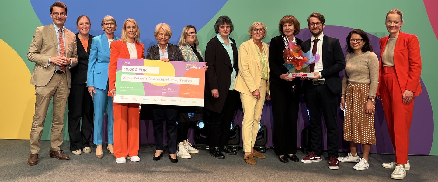 Gruppenbild mit zwölf Personen. Die Trophäe über den zweiten Preis und der Scheck mit dem Preisgeld von 30.000 Euro werden in die Höhe gehalten.