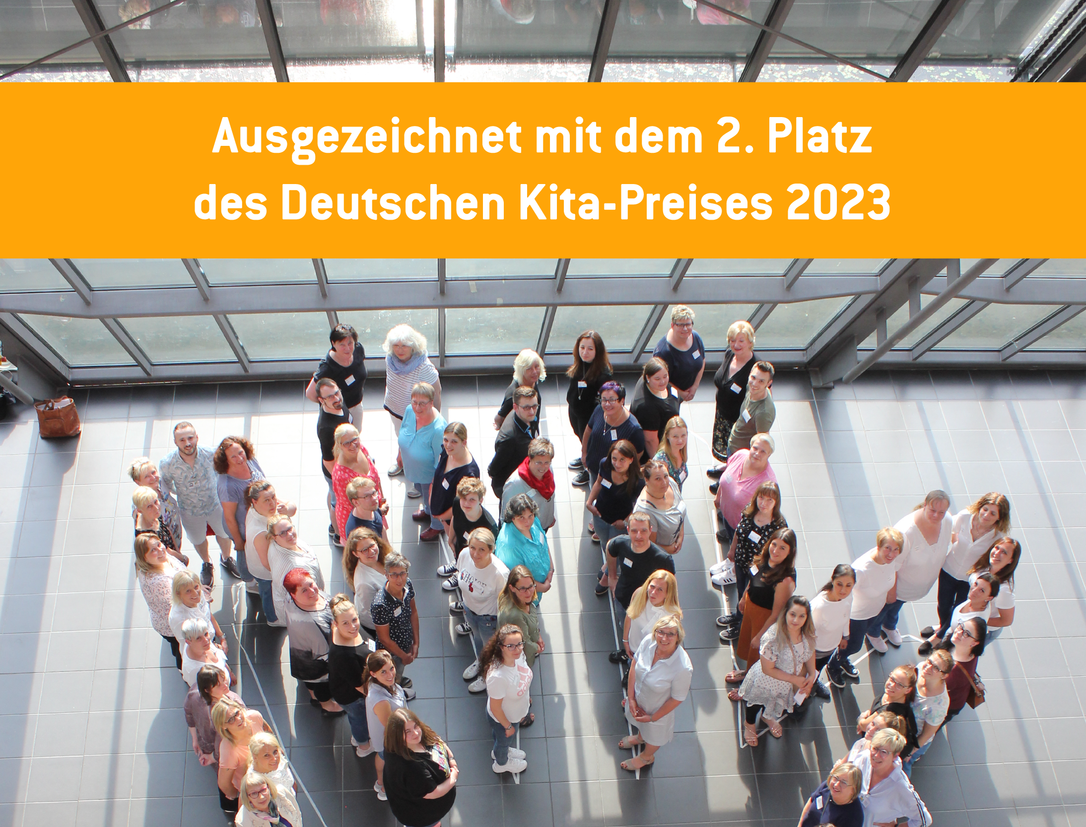 Bild der Gruppe von Projektbeteiligten. Auf einem Banner steht "Ausgezeichnet mit dem 2. Platz des Deutschen Kita-Preises 2023".