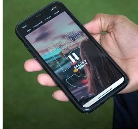 Eine Person hält ein Smartphone in der Hand. Auf diesem ist das Logo von "Salon5" zu sehen.