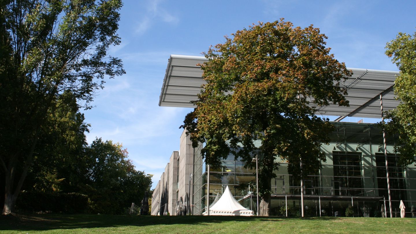 Außenansicht des Ruhrfestspielhauses bei blauem Himmel und Bäumen mit grünen Blättern