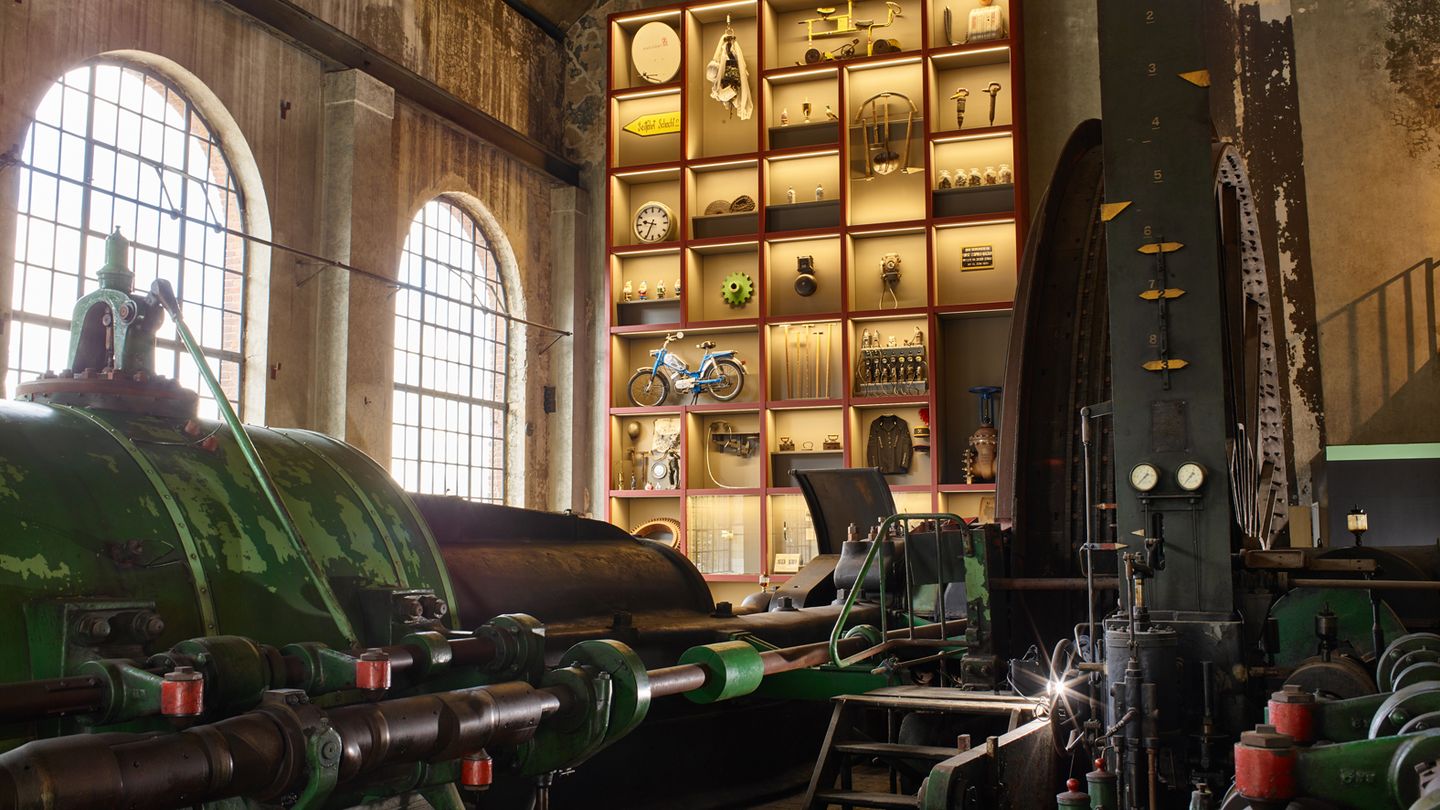 Inneneinblick in Gebäude der Zeche Fürst Leopold, darin eine große Maschine sowie ein Regal mit Alltagsgegenständen wie Uhren oder Fahrrädern